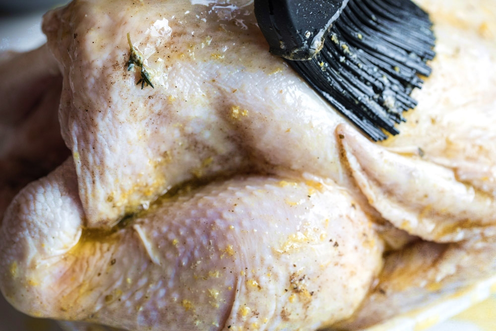 Using a pastry brush, rub the herb butter mixture over the entire chicken.