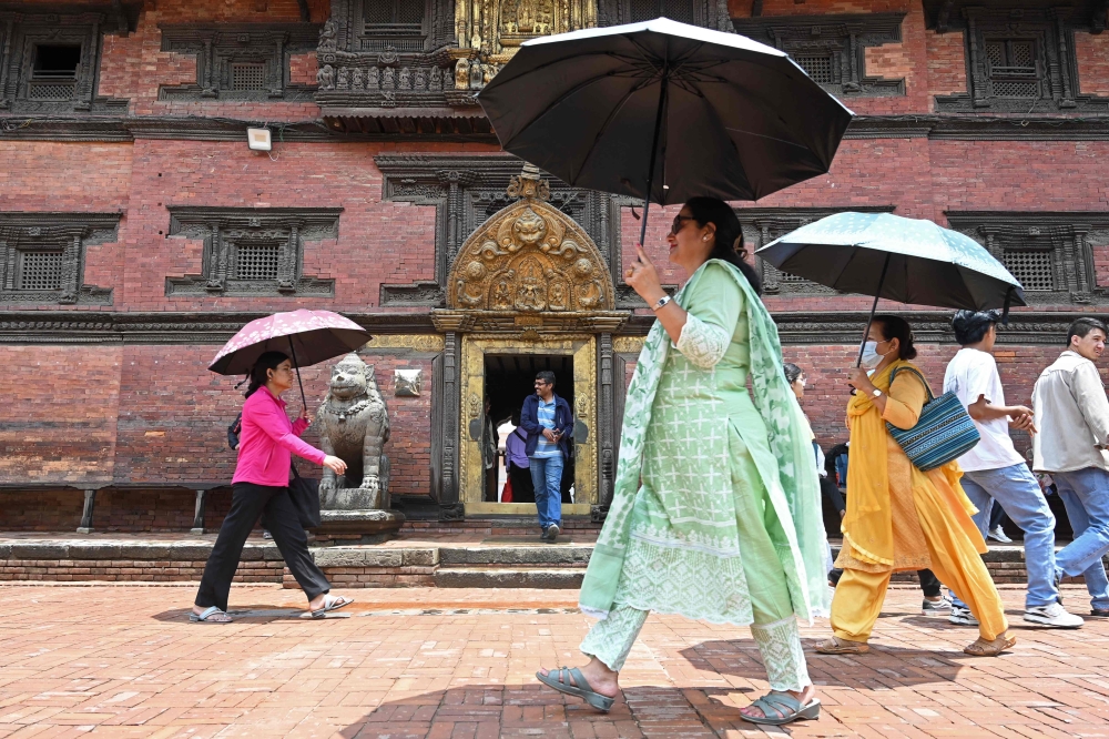 Pedestrians carry umbrellas to shelter from the heat on a summer afternoon at Durbar Square in Patan on the outskirts of Kathmandu on May 9, 2024. — ETX-Relaxnews pic