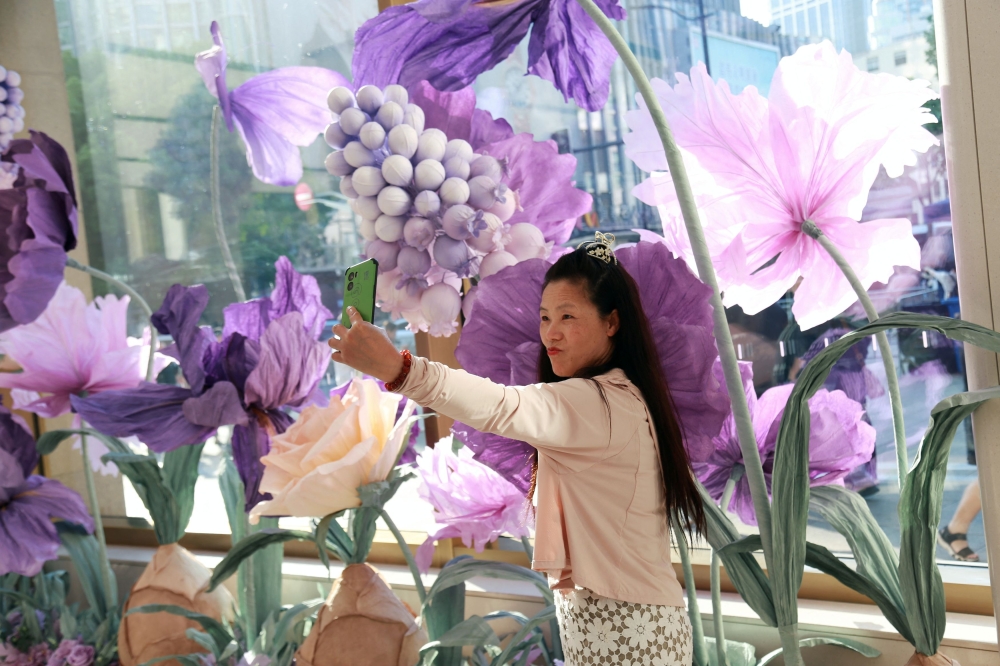 A woman takes pictures with a flower display at Huawei's flagship store in Shanghai. — Reuters pic