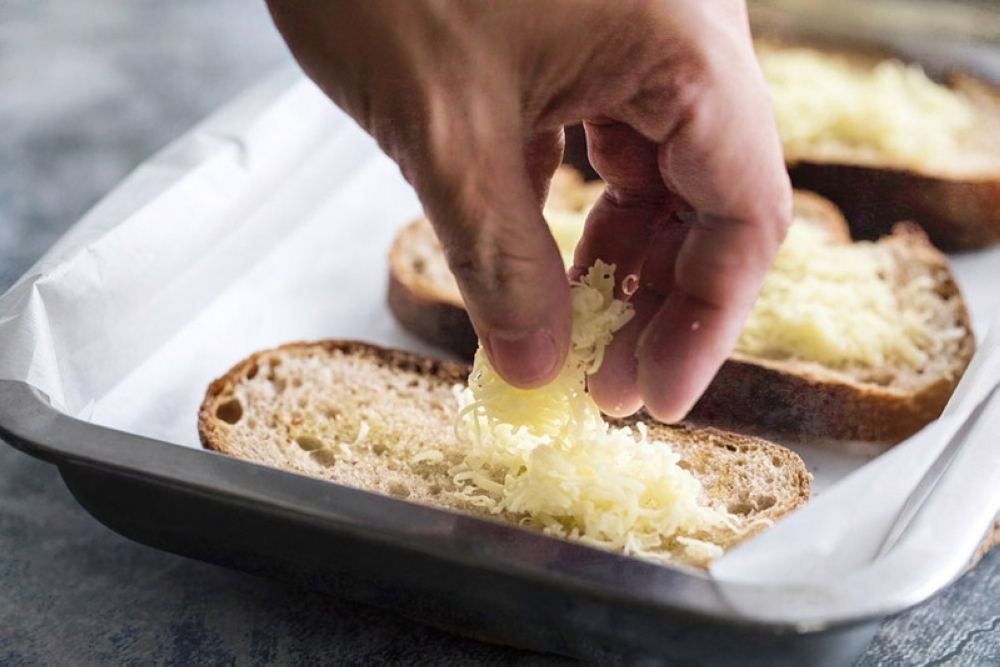 Sprinkle a handful of grated Cheddar cheese over each slice of bread.