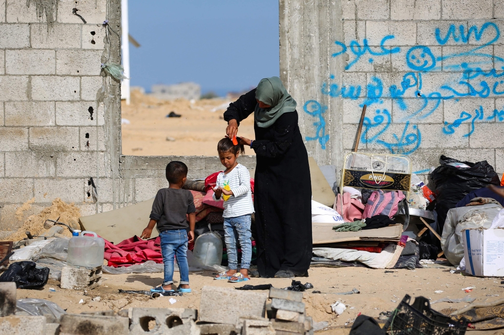 A displaced Palestinian combs her daughter’s hair at a temporary camp in Rafah on May 17, 2024, amid the ongoing conflict between Israel and the militant group Hamas. — AFP pic