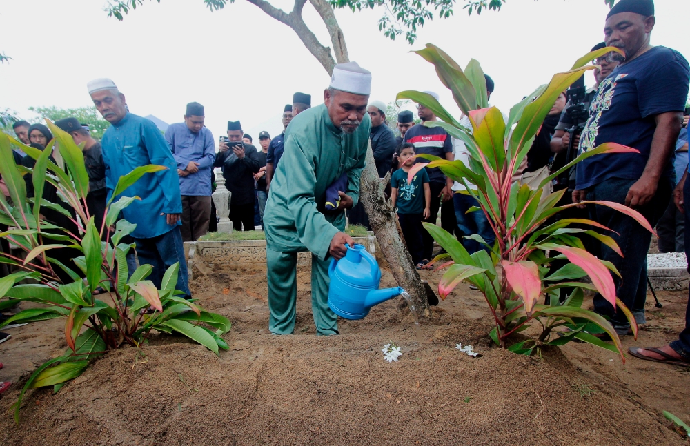 Ahmad Said Md Piah, 65, pours rose water on the grave of his son Constable Muhamad Syafiq Ahmad Said after he was laid to rest at the Batu 8 Muslim Cemetery, Gambang, Kuantan May 18, 2024. — Bernama pic