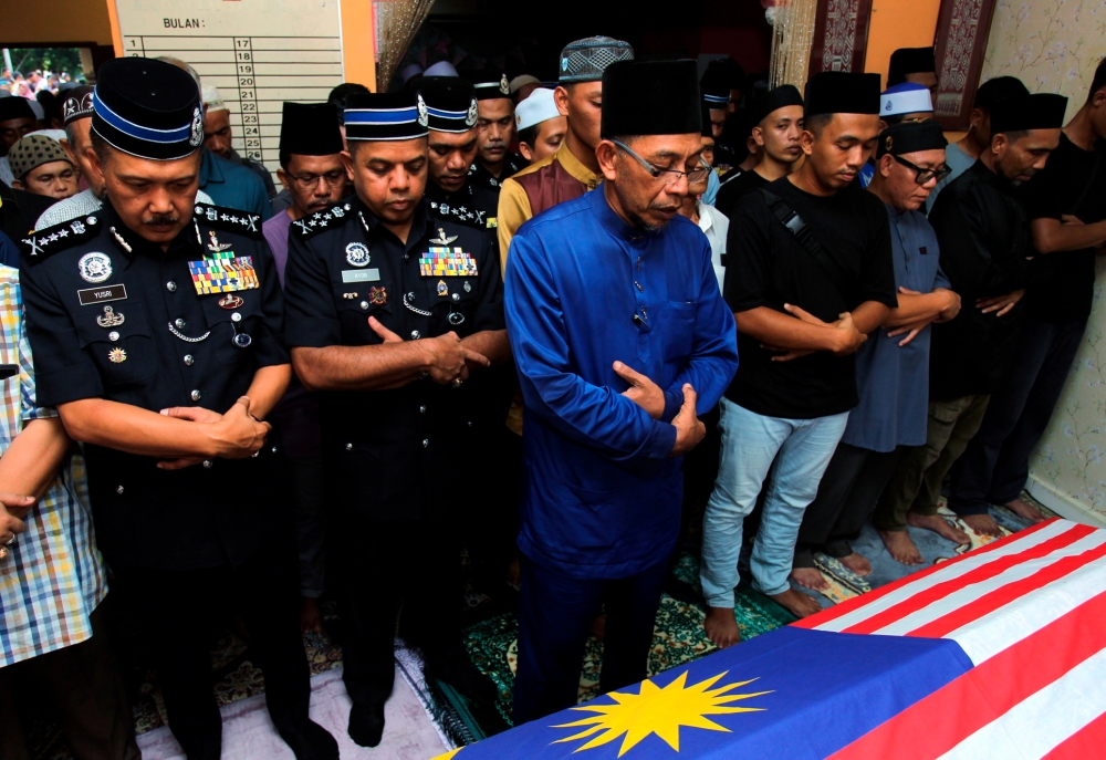 Deputy Inspector-General of Police Datuk Seri Ayob Khan Mydin Pitchay (2nd left) is present as Azhar Khaiden (front), father of late Constable Ahmad Azza Fahmi Azhar, lead prayers at his home in Kampung Poh Tambahan, Bidor May 18, 2024. — Bernama pic