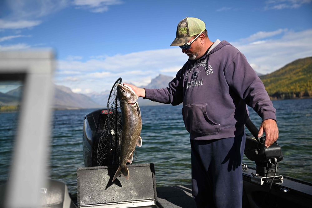 A fisherman, who declined to give his name, displays a lake trout, considered an invasive species, that he caught on Lake McDonald in Glacier National Park in Montana on October 18, 2023. — AFP pic