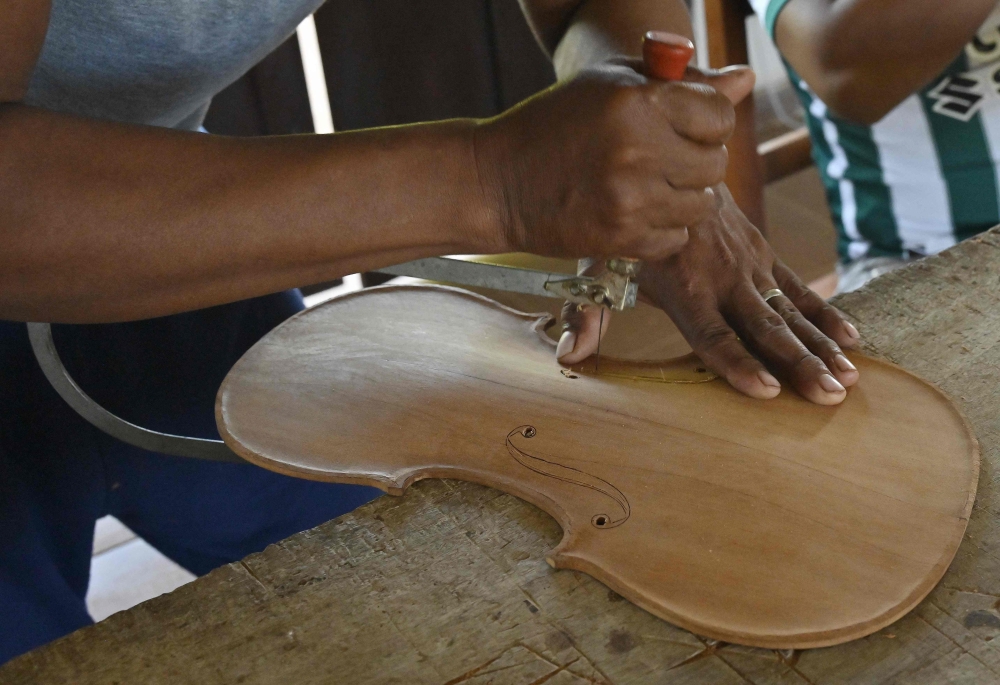 Nelson Orepocanga, a student of Formacion Artistica Coro y Orquesta Urubicha, carves a piece of wood to make a violin in the town of Urubicha, Bolivia April 22, 2024. — AFP pic
