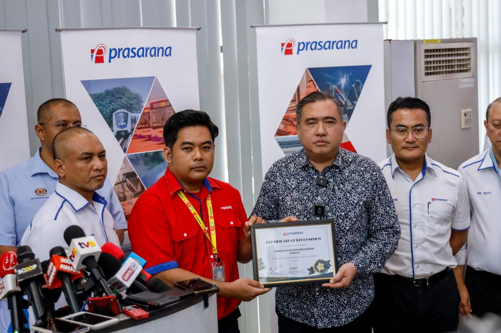 Transport Minister Anthony Loke presents a certificate of appreciation to Transit Officer Ahmad Zahiruddin Nordin for his quick action when an uprooted tree fell on the monorail tracks on May 7, at Wisma Monorail, Brickfields, May 23, 2024. — Picture by Firdaus Latif