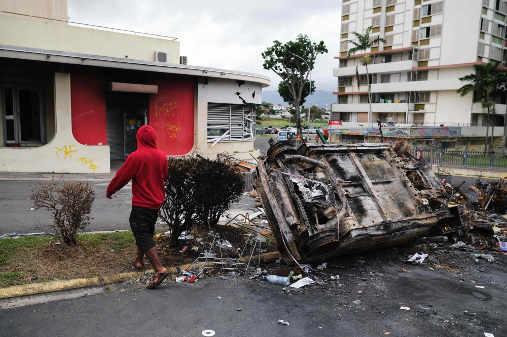  A man walks past a burnt vehicle at an independantist roadblock at Magenta Tour district in Noumea, France's Pacific territory of New Caledonia May 22, 2024. — AFP pic