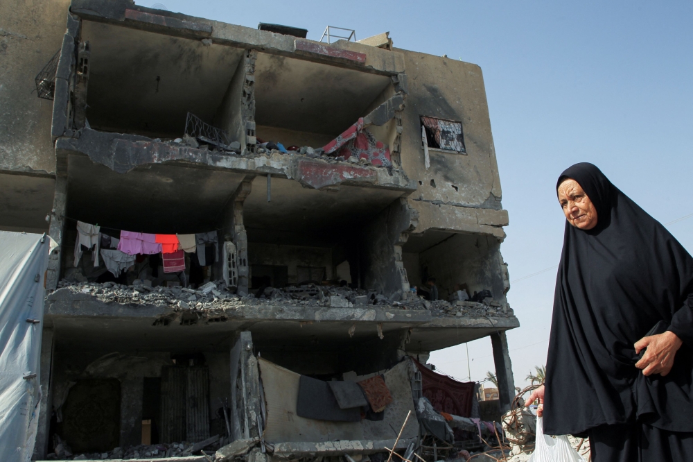 A Palestinian woman walks past a house destroyed by an Israeli strike, amid the ongoing conflict between Israel and the Palestinian Islamist group Hamas, in Rafah, southern Gaza Strip May 22, 2024. ― Reuters pic