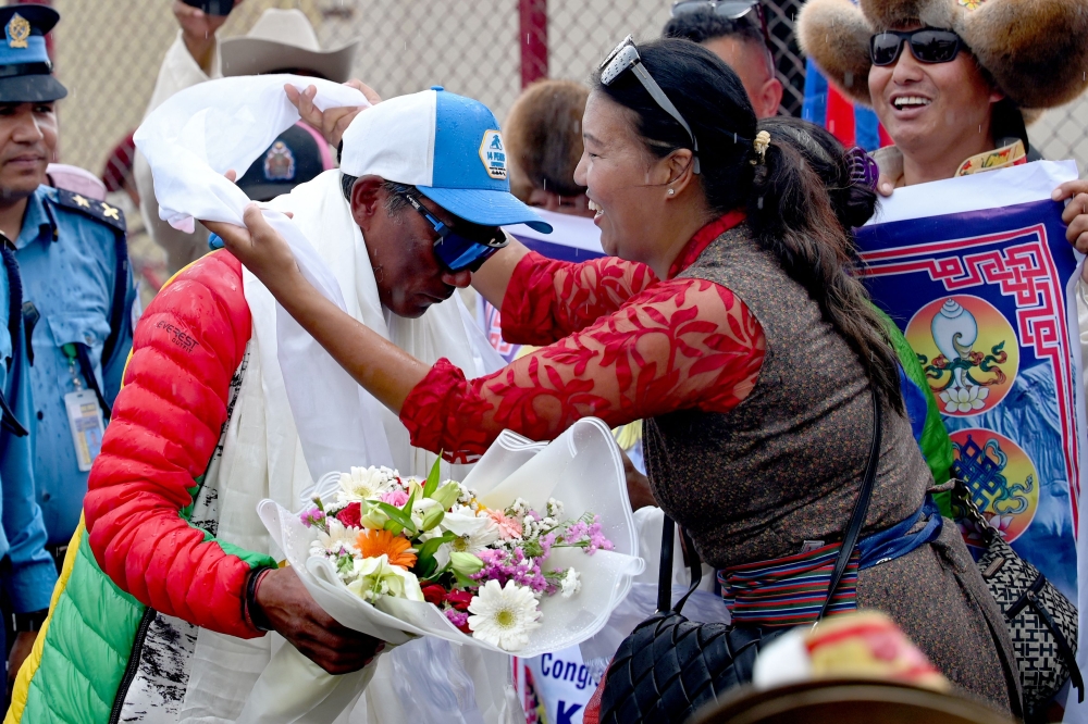 Nepali mountaineer Kami Rita Sherpa (2nd left), who broke his own record for scaling Mount Everest for the 30th time, is greeted by the crowd upon his arrival at the Tribhuvan International airport in Kathmandu on May 24, 2024. — AFP pic