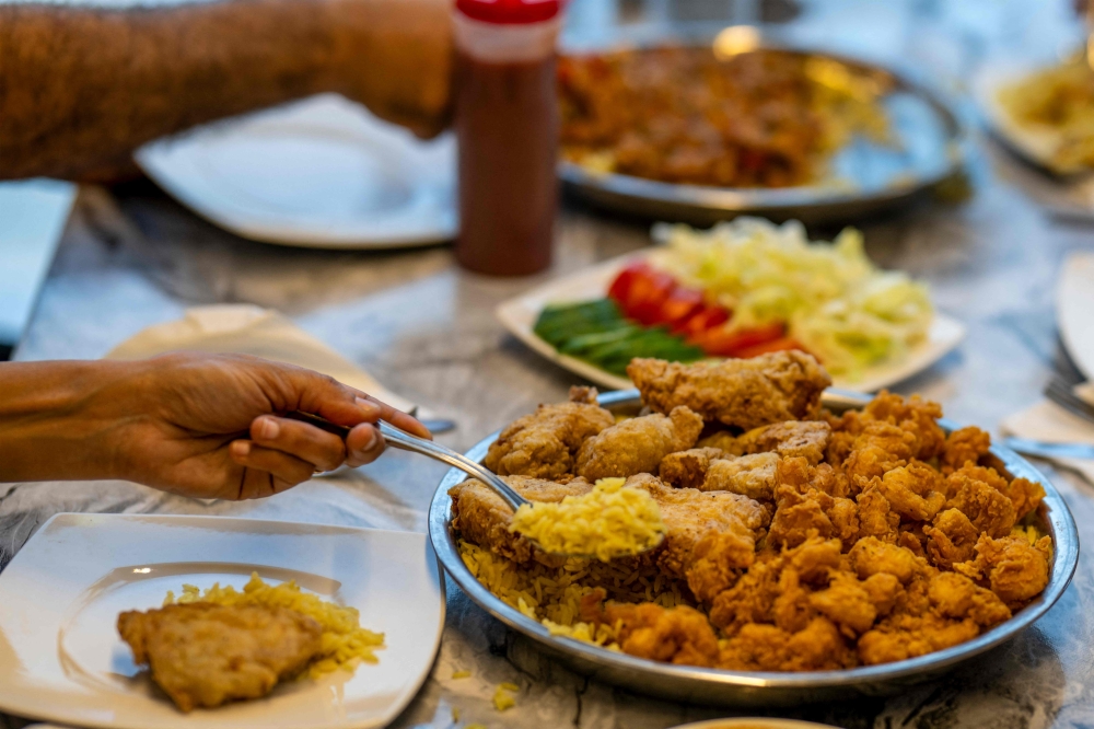 Clients are served traditional Sudanese food at a restaurant run by a businesswoman who relocated to the Egyptian capital Cairo after fleeing the ongoing war in Sudan May 21, 2024. — AFP pic