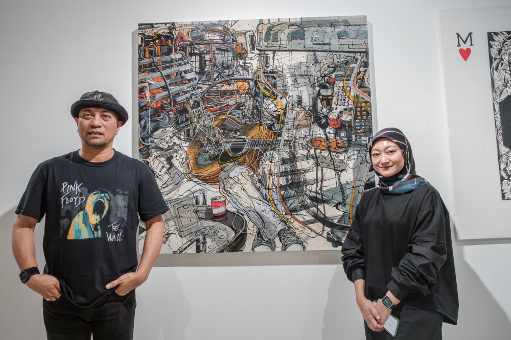 Galeri Puteh co-founders Nizam Rahmat and Mimie Abdullah pose with Husin Othman’s artwork inspired and named after M. Nasir’s 1986 hit, ‘Sesat di Kuala Lumpur’ ― Picture by Raymond Manuel