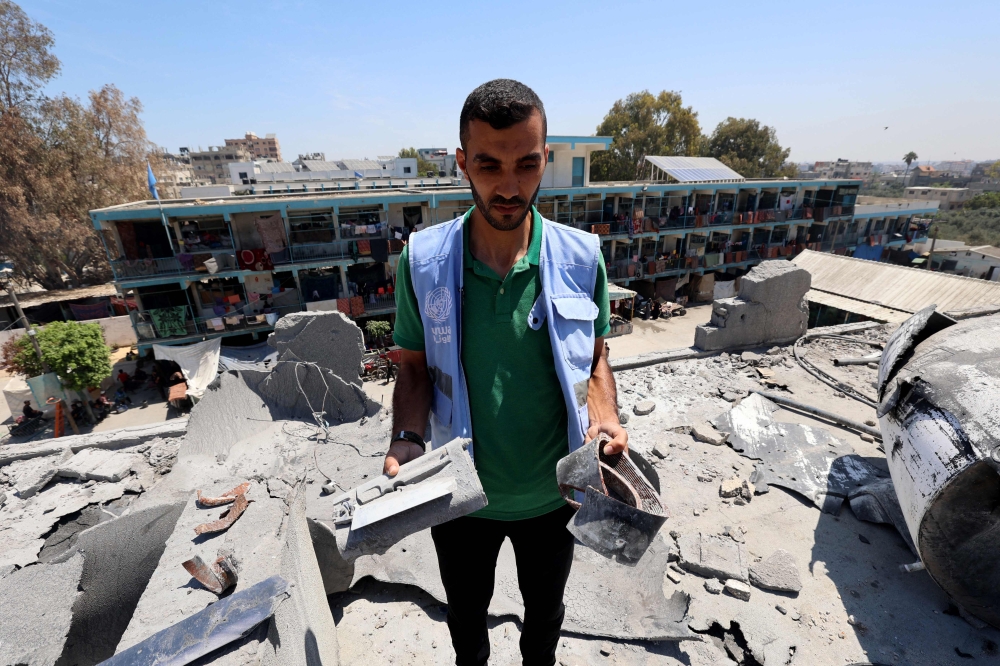 A member of a United Nations investigation team holds large chunks of shrapnel during a visit by investigators of a school run by the UN Relief and Works Agency for Palestine Refugees (UNRWA) which was hit during an Israeli army strike the day before, in the Nuseirat camp in the central Gaza Strip on June 7, 2024, amid the ongoing conflict in the Palestinian territory between Israel and Hamas. ― AFP pic