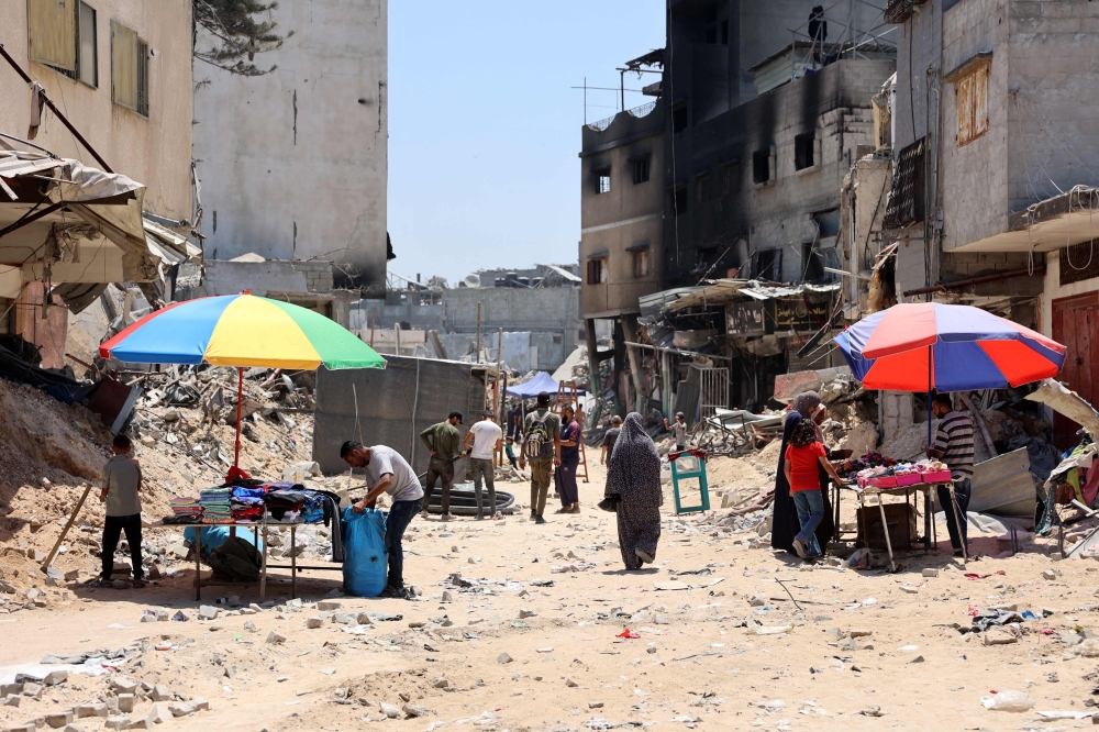 A woman walks past stalls set-up by vendors close to the ruins of destroyed buildings in the Jabalia refugee camp, in the northern Gaza Strip on June 7, 2024, amid the ongoing conflict between Israel and the Palestinian Hamas militant group. ― AFP pic