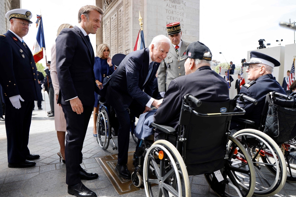 France’s President Emmanuel Macron (left) and US President Joe Biden (centre) speak to French WWII veteran Jacques Levis, who landed on Utah beach on D-Day alongside US troops, during a ceremony at the Arc of Triomphe, in Paris, on June 8, 2024. ― AFP pic