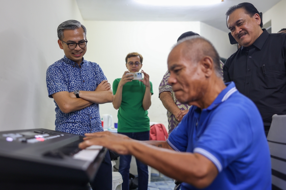 Communications Minister Fahmi Fadzil visits and presents a keyboard to renowned 80s composer and musician Roslan Ariffin Jamil (seated), better known as Ross Ariffin, at his home at the People’s Housing Project (PPR) in Kampung Muhibbah in Kuala Lumpur June 8, 2024. — Bernama pic