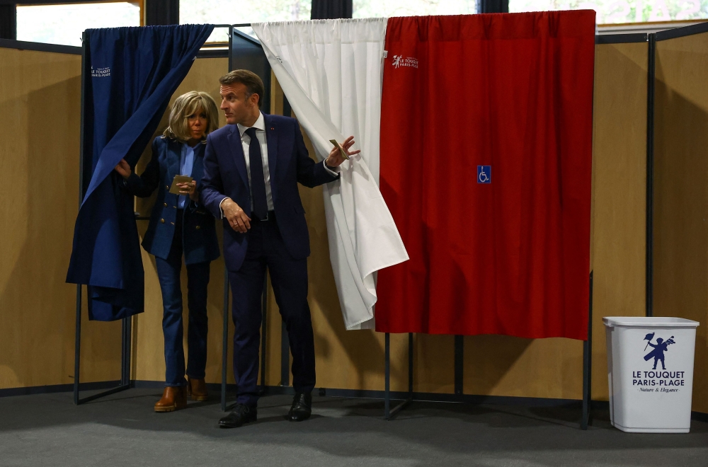 French President Emmanuel Macron and his wife Brigitte Macron exit voting booths during the European Parliament election, at a polling station in Le Touquet-Paris-Plage June 9, 2024. — Hannah McKay/Pool/Reuters pic  