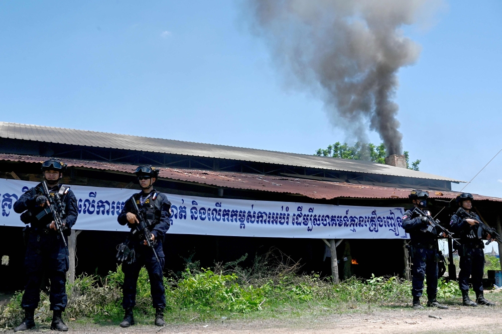 Military police stand guard in front of smoke rising from burning drugs during a destruction ceremony to mark the UN’s ‘International Day against Drug Abuse and Illicit Trafficking’ in Phnom Penh June 14, 2024. — AFP pic