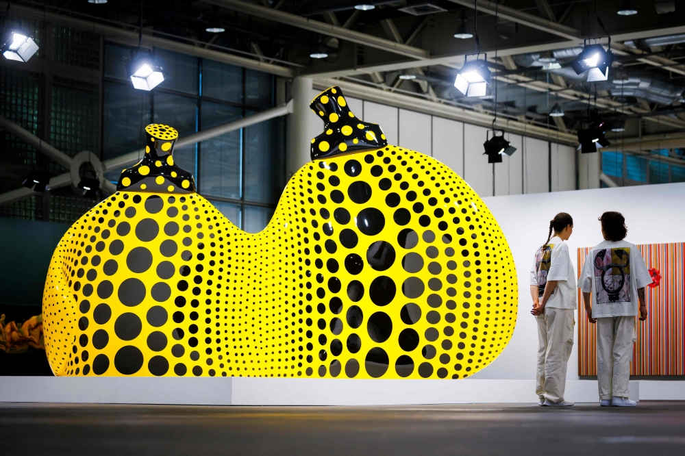 Art Basel's staff members stand next to by ‘Aspiring to Pumpkin’s Love, the Love in My Heart’ 2023, by Japanese artist Yayoi Kusama displayed at the Unlimited sector of Art Basel fair for Modern and contemporary art, in Basel June 11, 2024. — Valentin Flauraud/AFP pic