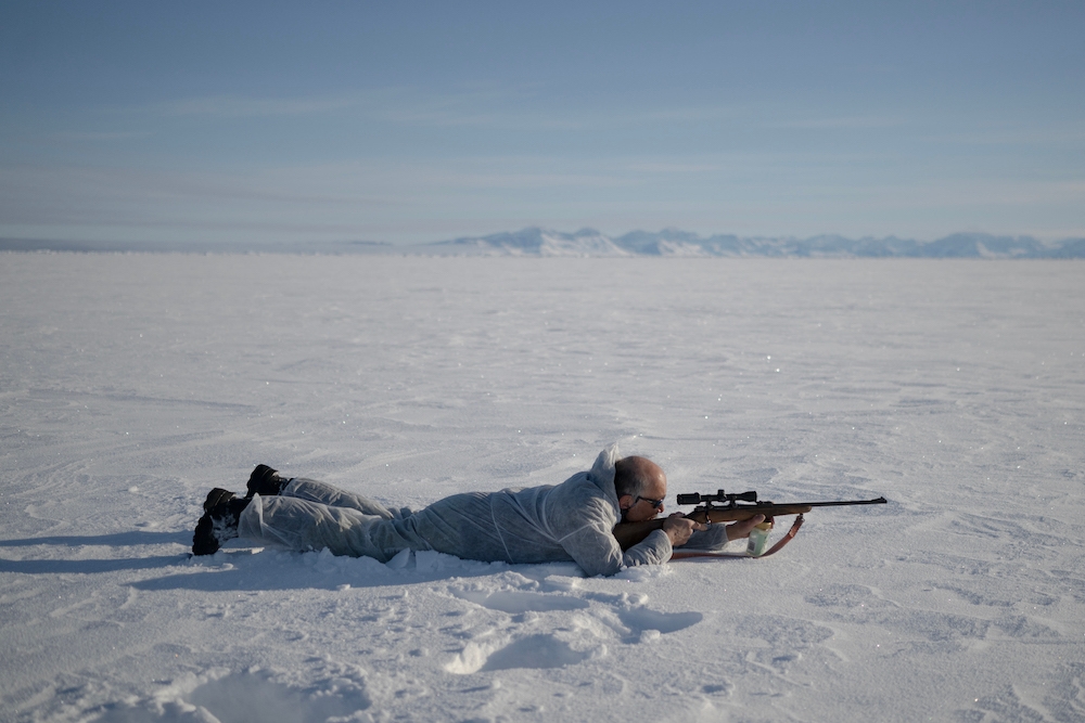 Inuit hunter Hjelmer Hammeken, 66 years old, wearing a white camouflage suit, aims at a seal he spotted 300m away, on the soft sea ice outside Ittoqqortoormiit on the frozen Scoresbysund Fjord on April 28, 2024. — AFP pic