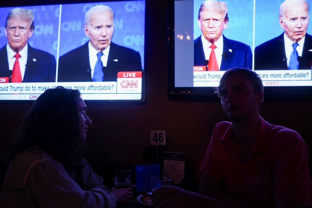Republican presidential candidate, former US President Donald Trump and Democrat presidential candidate, US President Joe Biden are seen on television as people attend a watch party for the first US presidential debate hosted by CNN in Atlanta, at Union Pub on Capitol Hill in Washington June 27, 2024. — Reuters pic