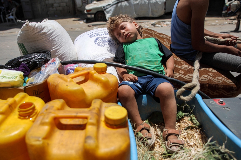 A boy sleeps on a sack of flour next to jerrycans in the back of an animal-drawn cart while evacuating from the Tuffah neighbourhood in the east of Gaza City heading towards areas in the west June 24, 2024 amid the ongoing conflict in the Palestinian territory between Israel and Hamas. — AFP pic