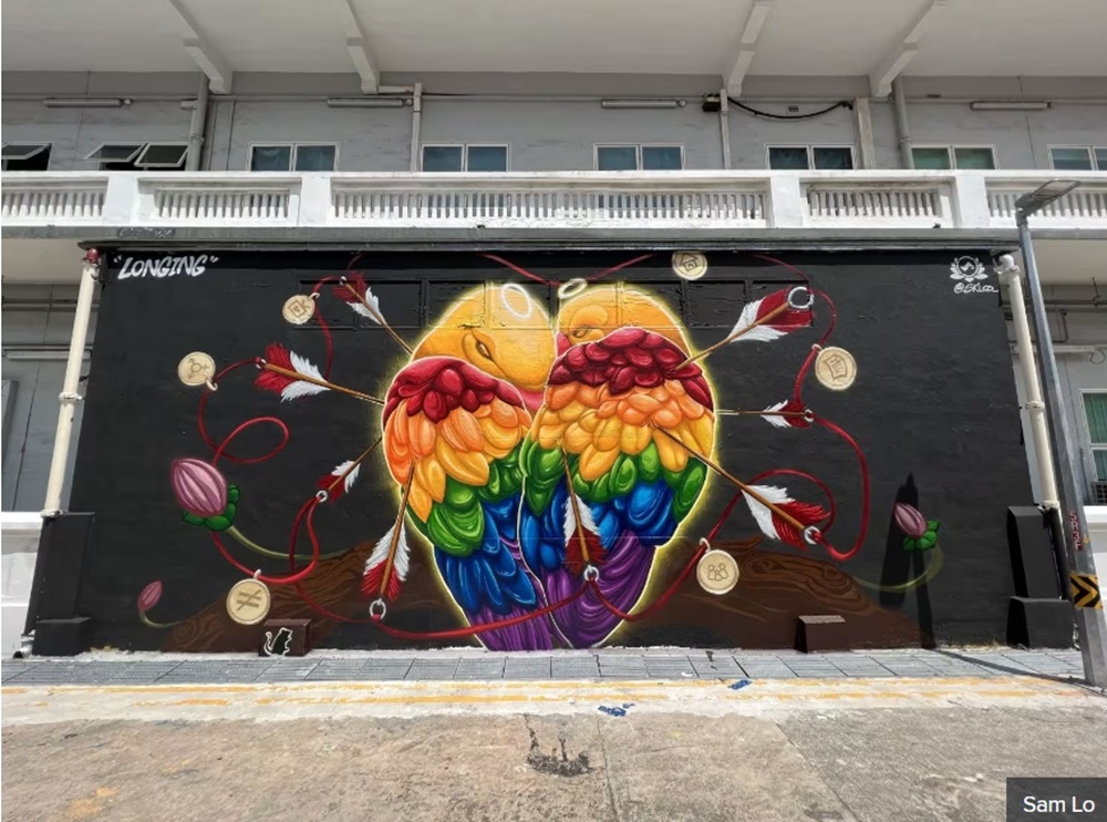 A mural done by Sam Lo that depicts a pair of lovebirds huddling together as arrows strike them. — Picture courtesy of Sam Lo