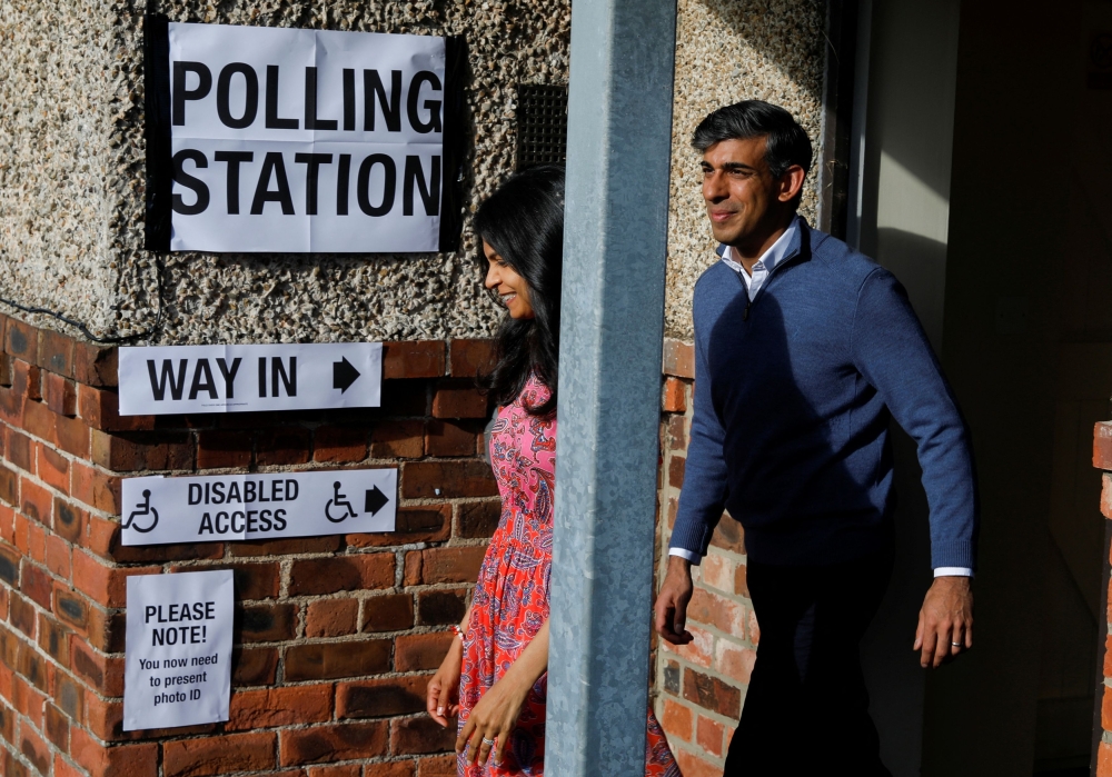 British Prime Minister Rishi Sunak and his wife Akshata Murty, walk out of a polling station during the general election in Northallerton. — AFP pic