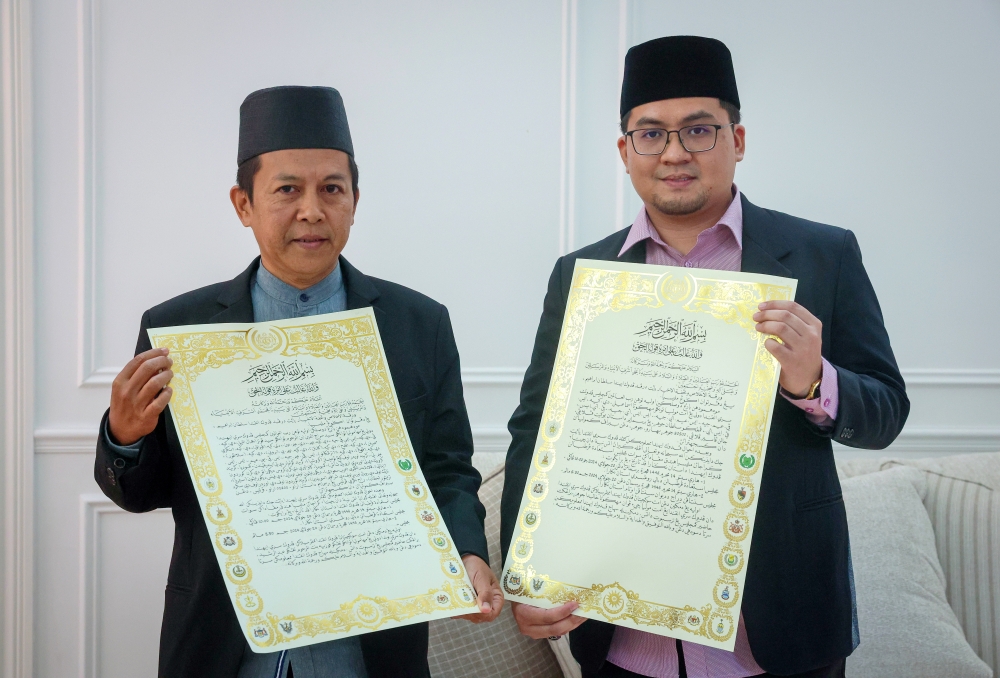 Calligrapher Abdul Baki Abu Bakar (left) and Chief coordinator of the Pahang Calligraphy Academy at Yayasan Pahang Khairi Izat Amir Mohd Izam show the invitation letter for the Installation Ceremony of Sultan Ibrahim as the 17th Yang di-Pertuan Agong. — Bernama pic