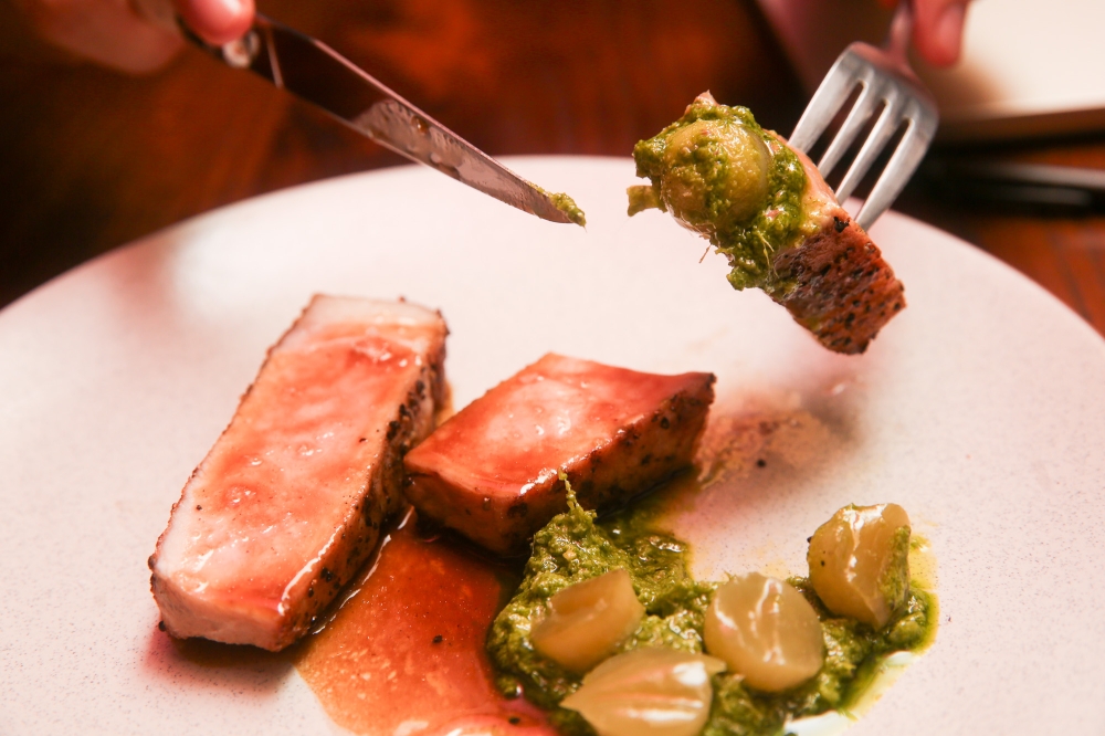 The pork chop is grilled and served with fermented bitter gourd and a wild garlic leaf pesto.