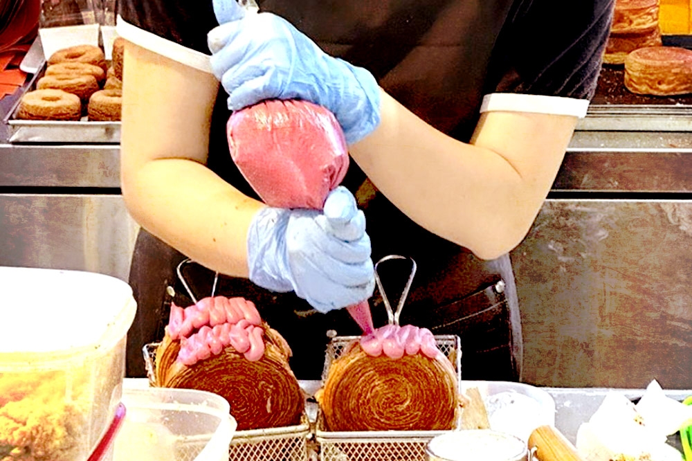 Piping cream filling into round croissants. — Picture by Lee Khang Yi