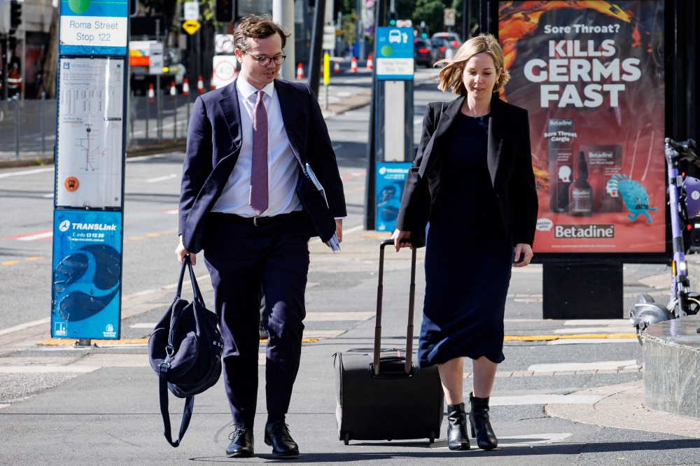 Barrister Dylan Kerr (left), representing the commissioner of the Australian Federal Police, arrives with an official at the Brisbane Watch House in Brisbane on July 12, 2024, where a 40-year-old woman and her 62-year-old husband — both holders of Russian passports — appeared before a magistrate after being charged with ‘preparing for an espionage offence’. — AFP pic