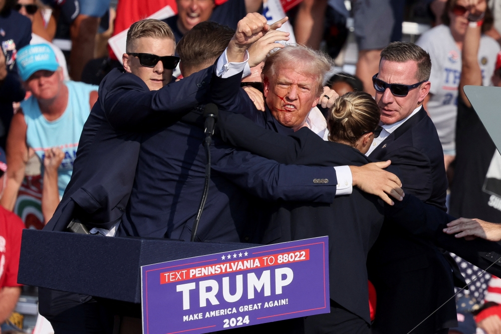 Former US president Donald Trump is escorted to safety moments after being shot at during a presidential campaign rally on July 13, 2024. — Reuters pic