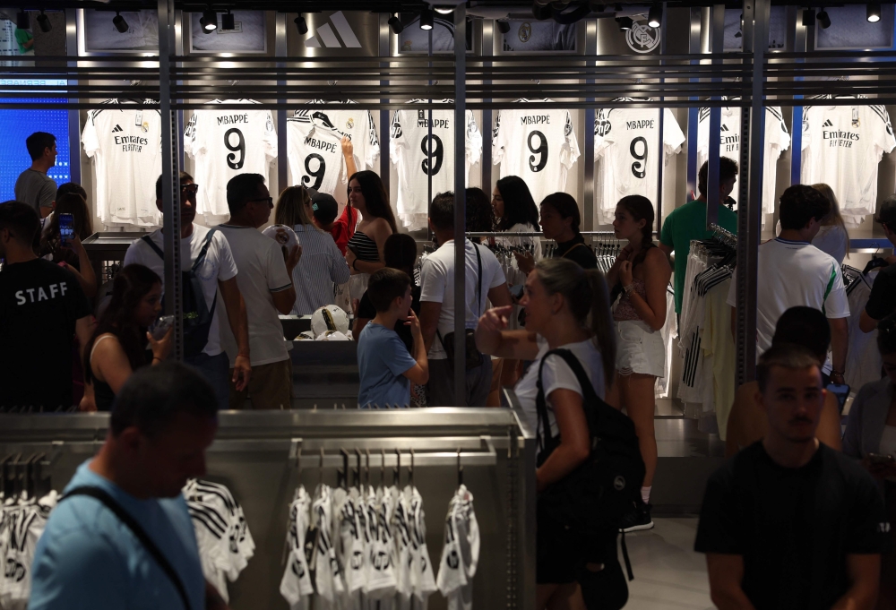 People buy the newly launched jersey of French footballer Killyan Mbappe at the Real Madrid's official store in the Santiago Bernabeu stadium in Madrid July 12, 2024. — Reuters pic  