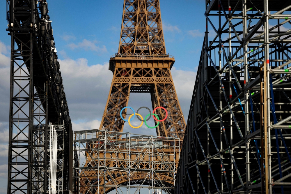 Olympic rings on the Eiffel Tower are seen through the construction site of Parc des Champions (Champion's Park) at the Trocadero for the upcoming Paris 2024 Olympic Games, in Paris July 4, 2024. — AFP pic