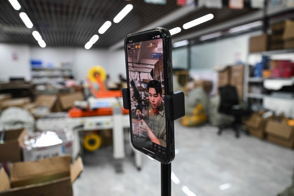 This photo taken on June 17, 2024 shows Ouyang (left) reacting during a livestream at an e-commerce company in Yiwu in east China's Zhejiang Province. — AFP pic