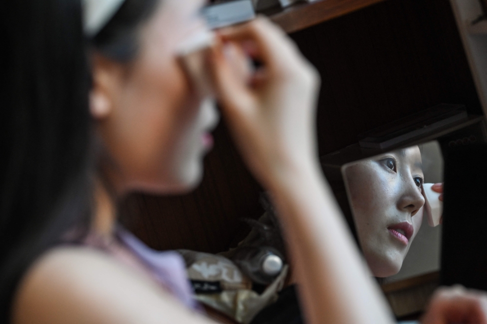 This photo taken on June 17, 2024 shows actress Guo Ting putting on make-up at her apartment in Hengdian in east China's Zhejiang Province. — AFP pic