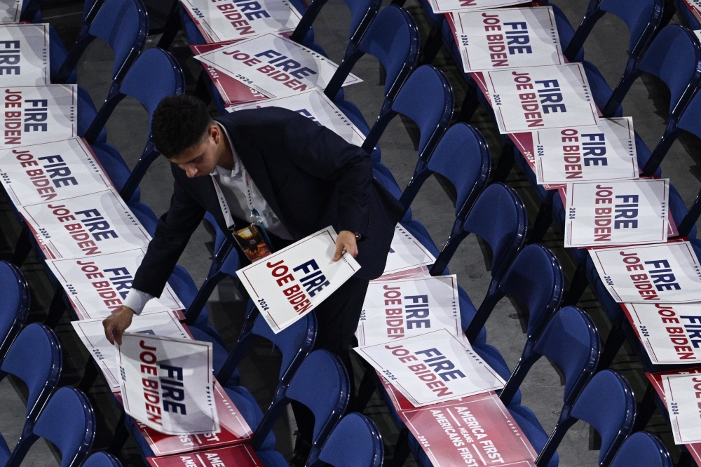 A worker sets signs reading ‘Fire Joe Biden’ on attendees seats during the last day of the 2024 Republican National Convention at the Fiserv Forum in Milwaukee, Wisconsin July 18, 2024. — AFP pic