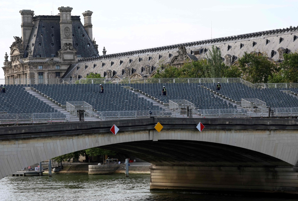 Workers inspecting the spectator stands on Pont du Carrousel over the River Seine in Paris. — AFP pic