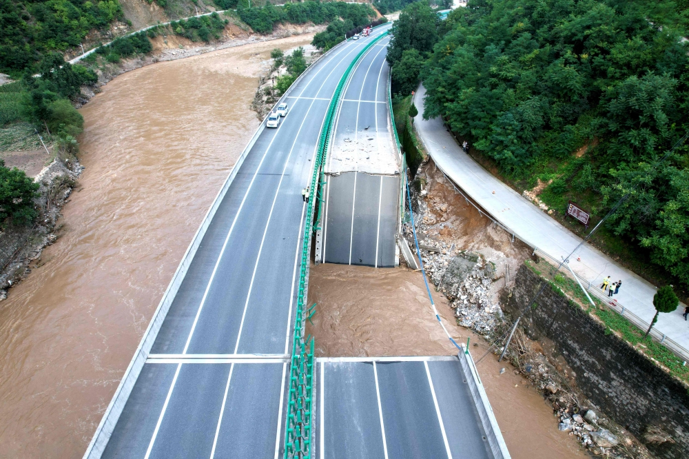 Several vehicles in northwestern Shaanxi province plunged into a swollen river late Friday after a bridge collapsed, with at least 12 people killed. — AFP pic