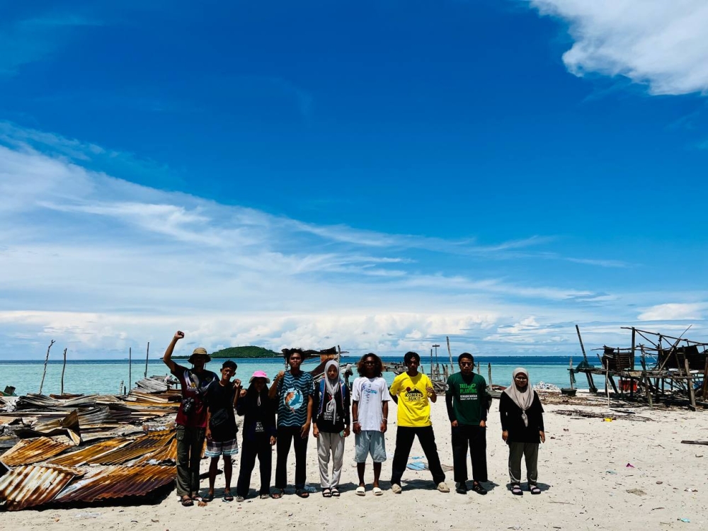 Mukmin Nantang and his Borneo Komrad crew standing in front of what was until recently a Bajau Laut settlement before it was dismantled. — Picture courtesy of Borneo Komrad