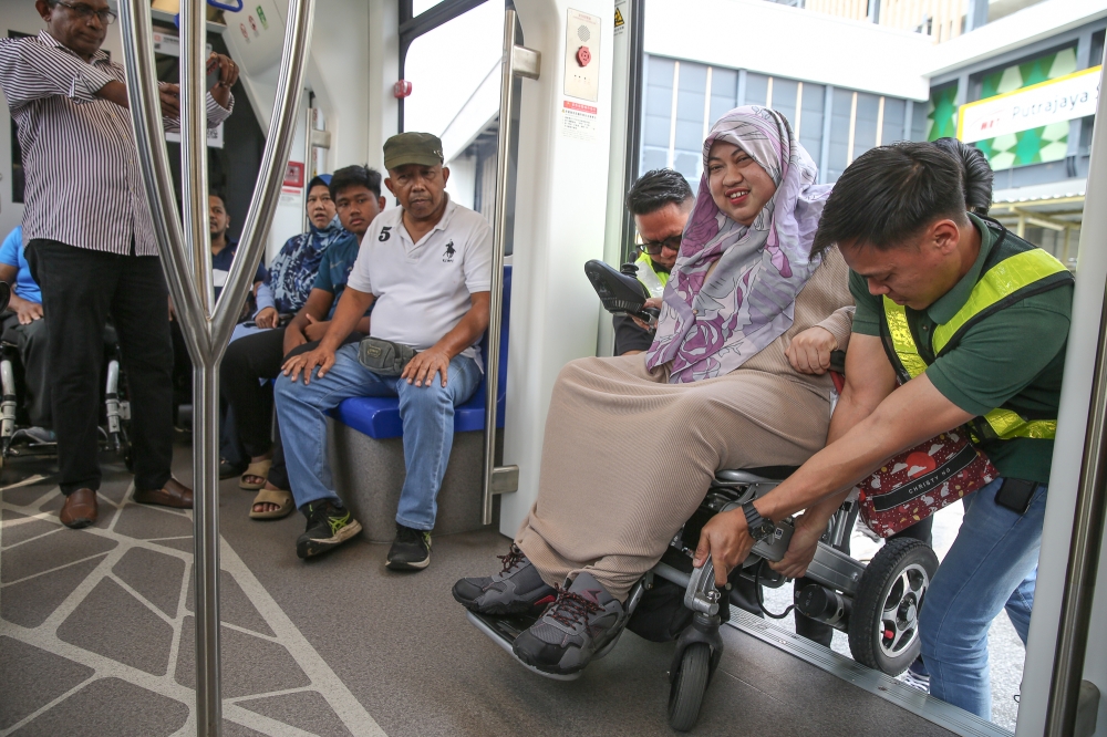 A wheelchair user is carried onto the trackless tram outside the Putrajaya Sentral Station in Putrajaya, on July 21, 2024. — Picture by Yusof Mat Isa