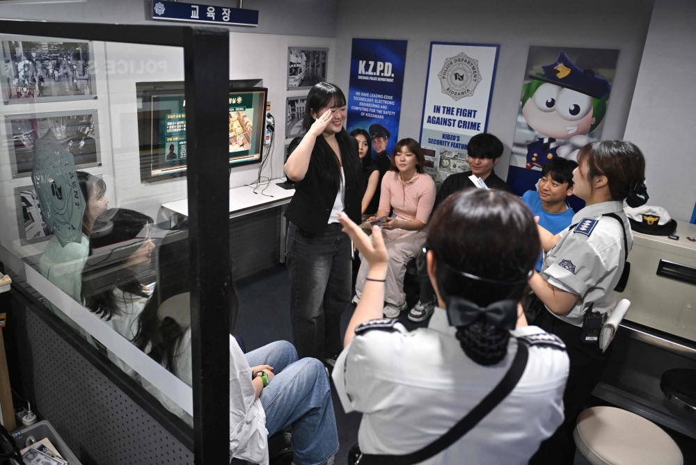 Visitors role-playing as policemen in a mock police station during an adult-only event at KidZania, a children’s job experience theme park, in Seoul June 28, 2024. — AFP pic