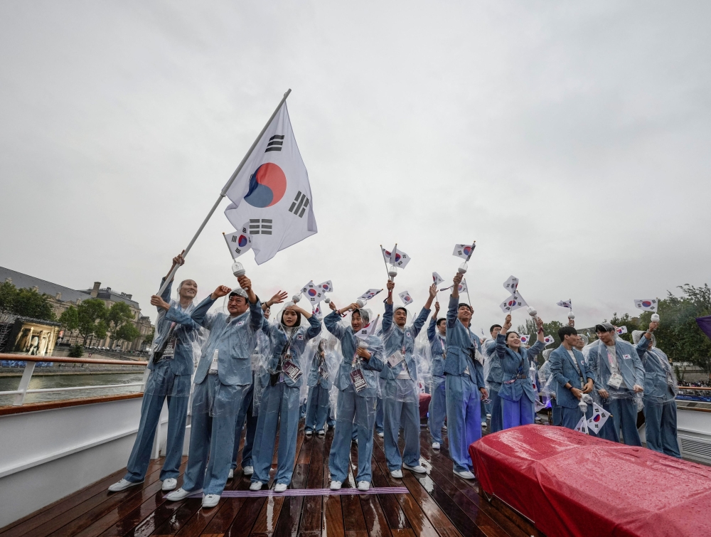 Team South Korea, wearing rain coats, wave their flag from a boat in Paris, France, during the opening ceremony of the 2024 Summer Olympics in Paris, July 26, 2024. — Reuters pic 