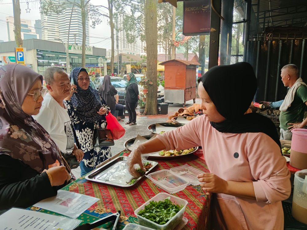 Saniah Mohammed Salim serves customers who come to buy various types of akok at her stall in Kampung Baru. — Bernama pic