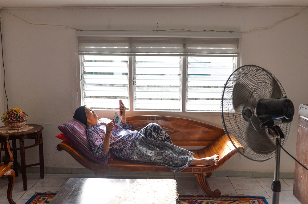 A file photograph shows a person cooling off beside a window in Shah Alam. — Picture by Miera Zulyana