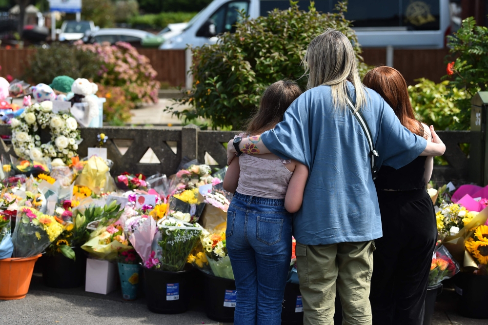 Residents look at floral tributes for the victims of a deadly knife attack in Southport, northwest England, July 31, 2024. — AFP pic