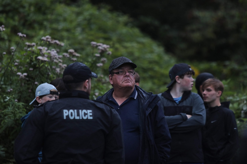 A police officer speaks to a group of protesters who gathered for the ‘Enough is Enough’ demonstration opposite protesters (not seen) defending the Abdullah Quilliam Mosque in Liverpool on August 2, 2024. — AFP pic