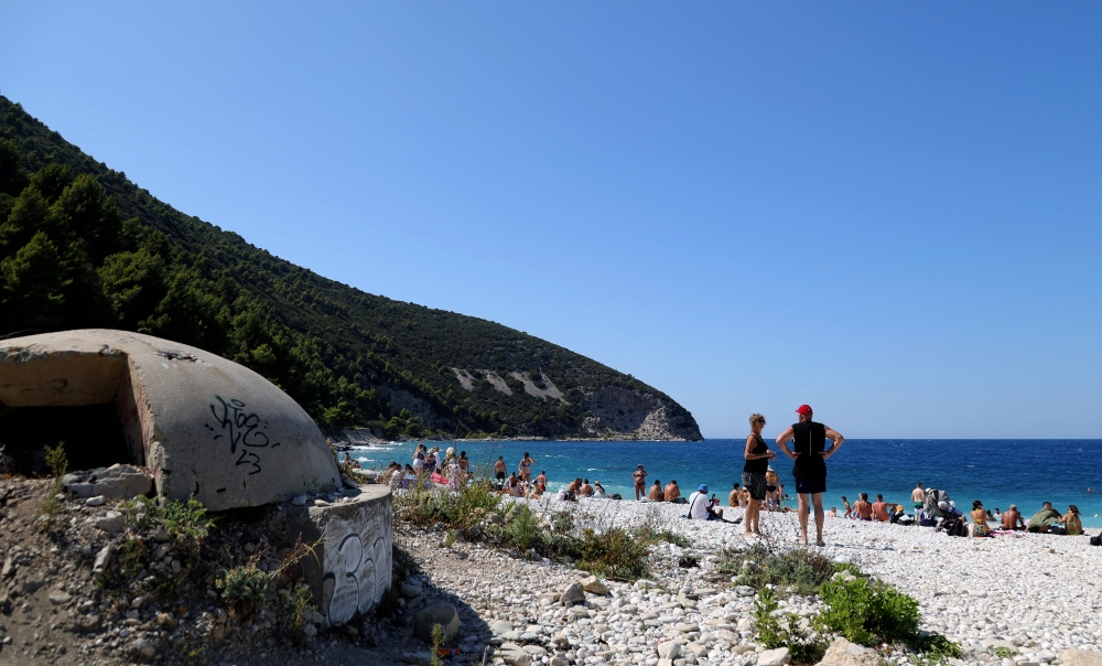 Tourists sunbathe near the remains of a bunker on the beach. — AFP pic