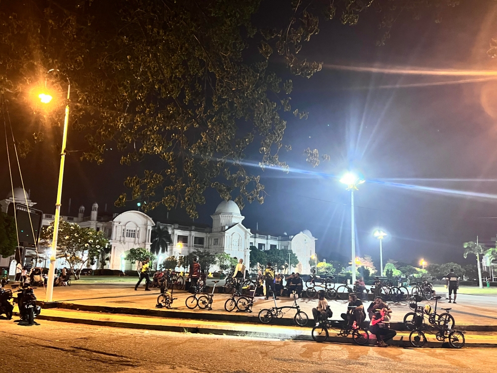 People cycle outside the Ipoh Railway Station at night. — Picture by John Bunyan