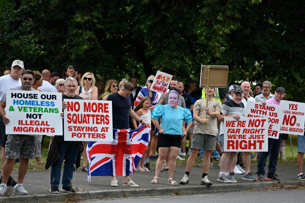 British far-right protesters, including one wearing a mask of Prime Minister Keir Starmer, demonstrate against asylum seekers in Aldershot on August 4, 2024. — AFP pic